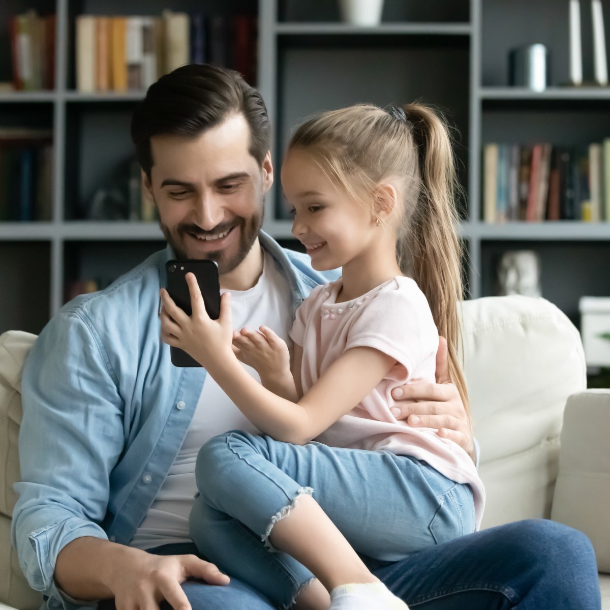 A father and his daughter looking at a smartphone